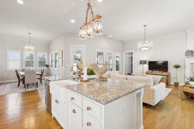 kitchen featuring white cabinetry, sink, pendant lighting, light hardwood / wood-style floors, and a kitchen island with sink