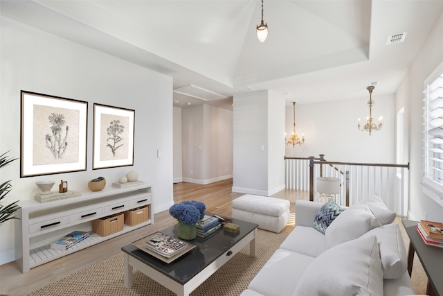 living room with a chandelier, light hardwood / wood-style floors, vaulted ceiling, and a healthy amount of sunlight