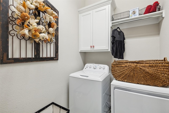 clothes washing area with washer and clothes dryer and cabinets