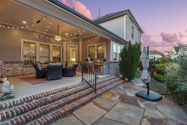 patio terrace at dusk featuring an outdoor kitchen