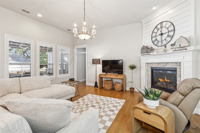 living room featuring a notable chandelier, light hardwood / wood-style floors, and a stone fireplace