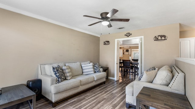 living area with wood finished floors, baseboards, a ceiling fan, and visible vents