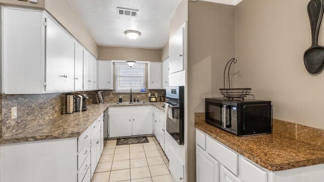 kitchen with white cabinetry, sink, backsplash, dark stone countertops, and black appliances