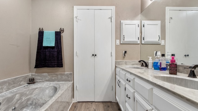 bathroom with a washtub, wood-type flooring, and vanity