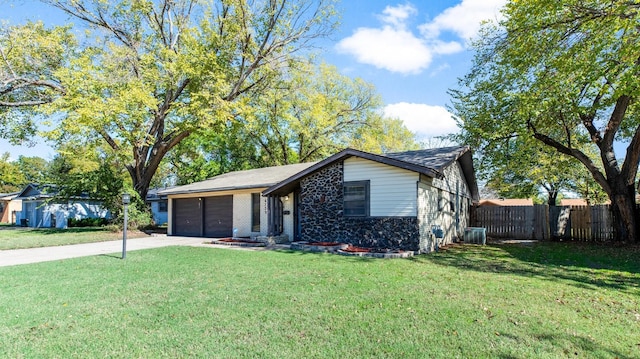 ranch-style home with fence, a front lawn, brick siding, an attached garage, and driveway