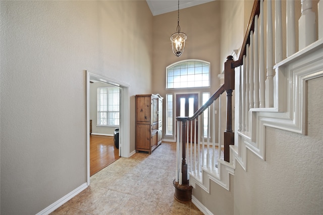 foyer featuring light hardwood / wood-style floors, a towering ceiling, and an inviting chandelier