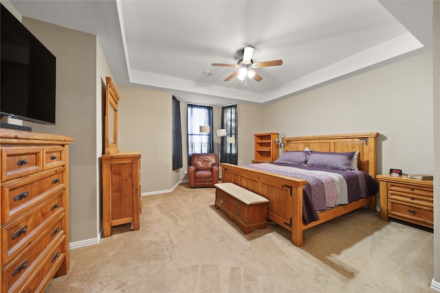 bedroom featuring ceiling fan, a raised ceiling, and light carpet