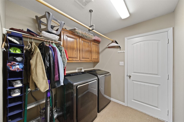 laundry area featuring cabinets, light colored carpet, washer and dryer, and a textured ceiling