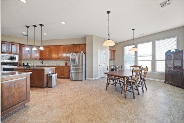 kitchen with decorative light fixtures, a center island, appliances with stainless steel finishes, and tasteful backsplash