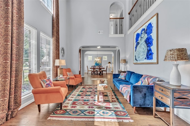 living room featuring hardwood / wood-style floors, a towering ceiling, and a healthy amount of sunlight