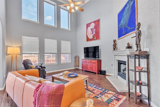 living room featuring ceiling fan, wood-type flooring, and a high ceiling