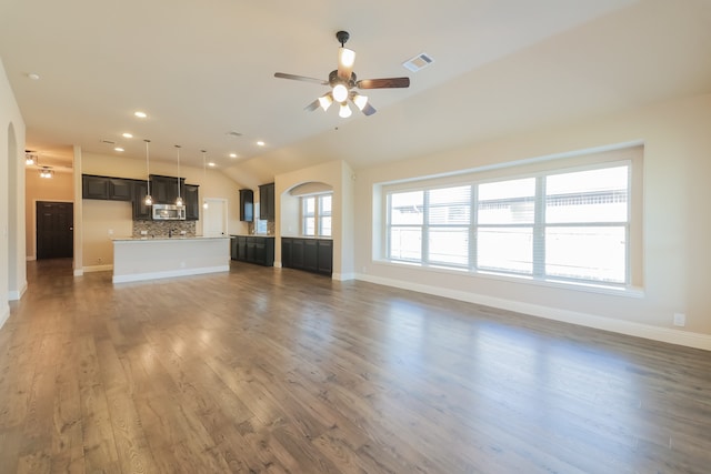 unfurnished living room featuring dark hardwood / wood-style floors, ceiling fan, and vaulted ceiling