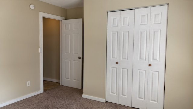 unfurnished bedroom with light colored carpet and a closet