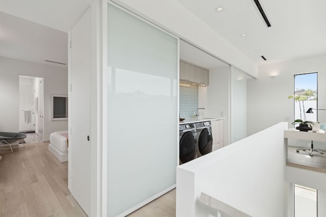 interior space with light wood-type flooring, sink, and separate washer and dryer