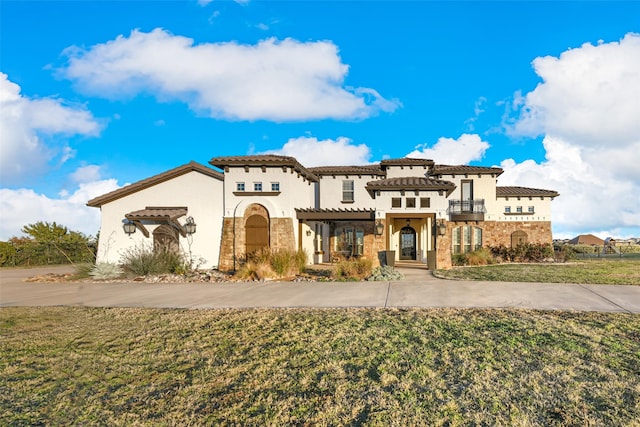 mediterranean / spanish home featuring a balcony and a front lawn