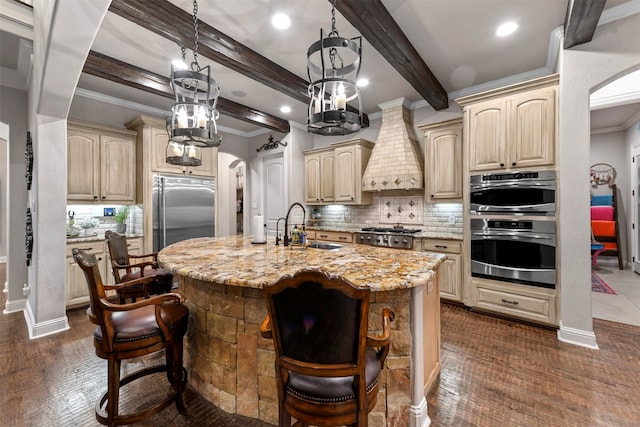 kitchen with appliances with stainless steel finishes, a breakfast bar, custom range hood, dark wood-type flooring, and a center island with sink