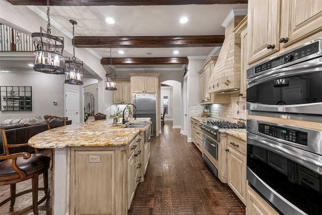 kitchen featuring pendant lighting, light brown cabinets, a kitchen island with sink, beamed ceiling, and light stone counters