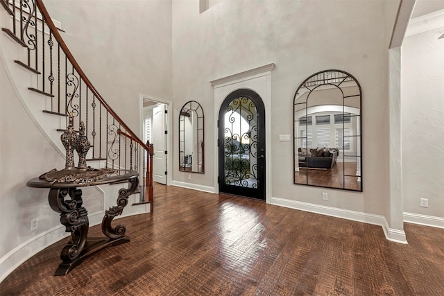 foyer featuring a towering ceiling, wood-type flooring, and ornamental molding