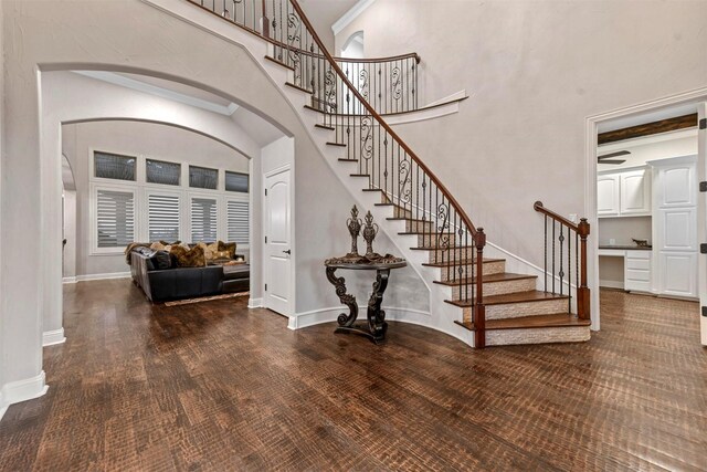 stairs featuring hardwood / wood-style flooring, a towering ceiling, and ornamental molding