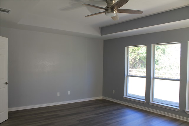 unfurnished room featuring dark hardwood / wood-style floors, ceiling fan, and a tray ceiling