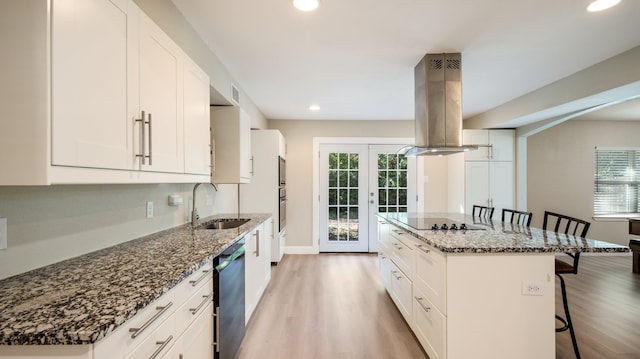 kitchen featuring a kitchen breakfast bar, island range hood, white cabinetry, and sink