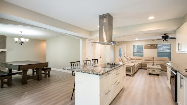 kitchen with a breakfast bar, dark stone counters, black appliances, white cabinetry, and island exhaust hood