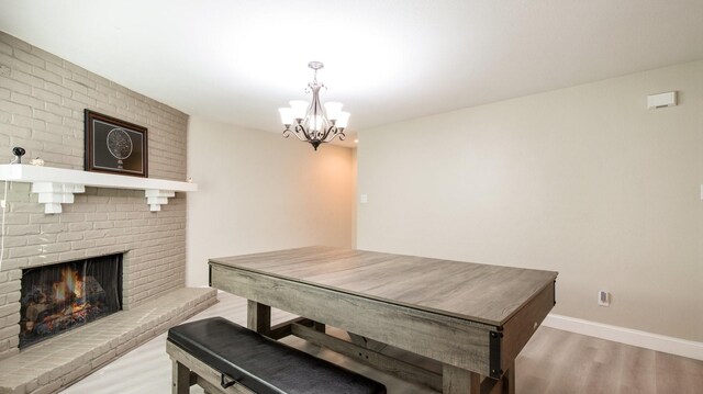 dining space with an inviting chandelier, light hardwood / wood-style floors, and a brick fireplace