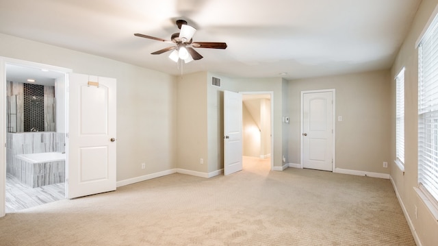 unfurnished bedroom with connected bathroom, light colored carpet, and multiple windows