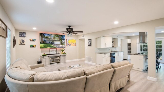 living room featuring ceiling fan, sink, and light hardwood / wood-style floors