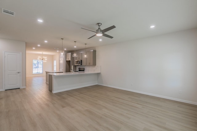 kitchen with gray cabinetry, light wood-type flooring, decorative light fixtures, kitchen peninsula, and ceiling fan with notable chandelier