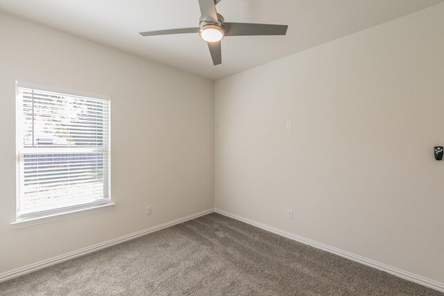 carpeted spare room featuring ceiling fan and baseboards