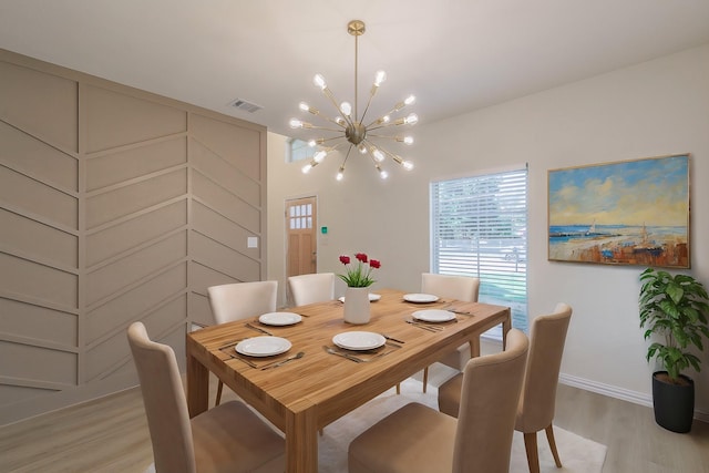 dining space with light hardwood / wood-style floors and a chandelier