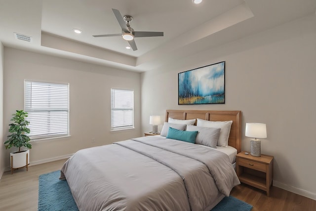 bedroom featuring multiple windows, a raised ceiling, and visible vents