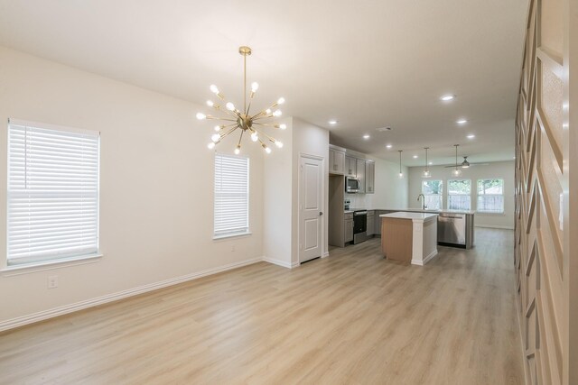 unfurnished living room with light hardwood / wood-style floors and ceiling fan with notable chandelier