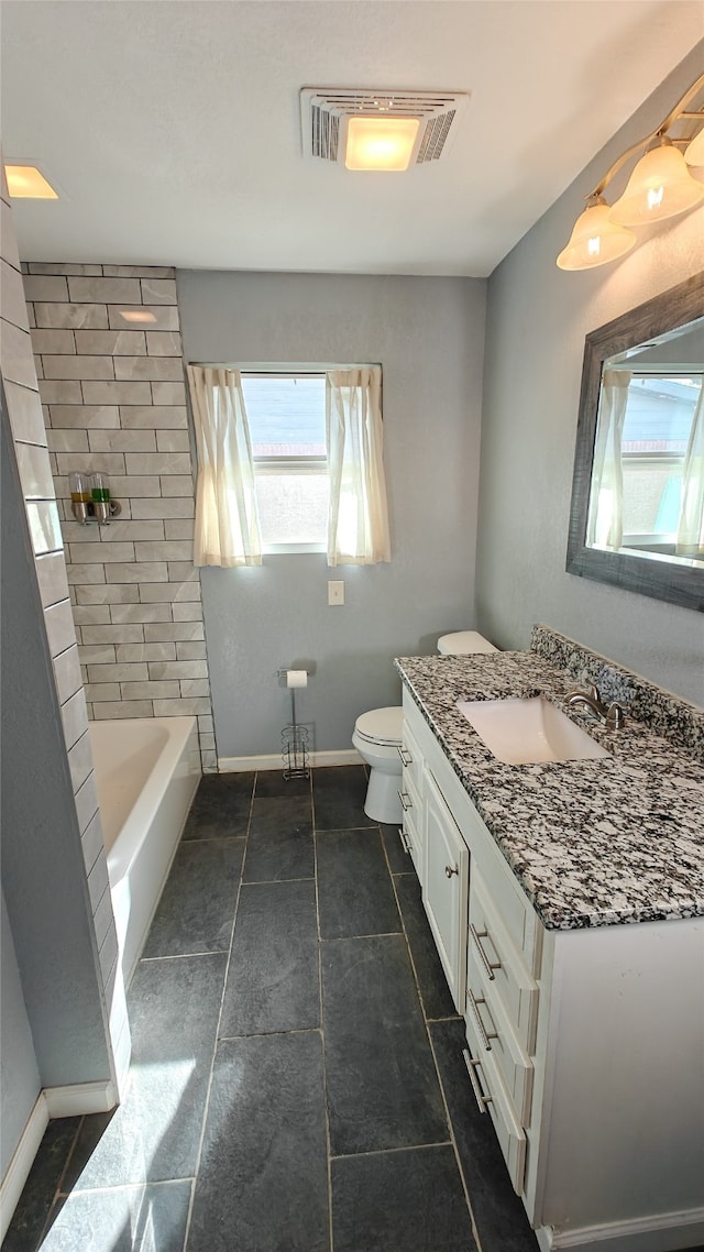 full bathroom featuring tile patterned floors, tiled shower / bath, vanity, and toilet