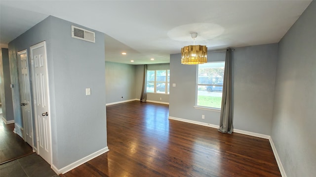 unfurnished room featuring dark hardwood / wood-style flooring and a chandelier