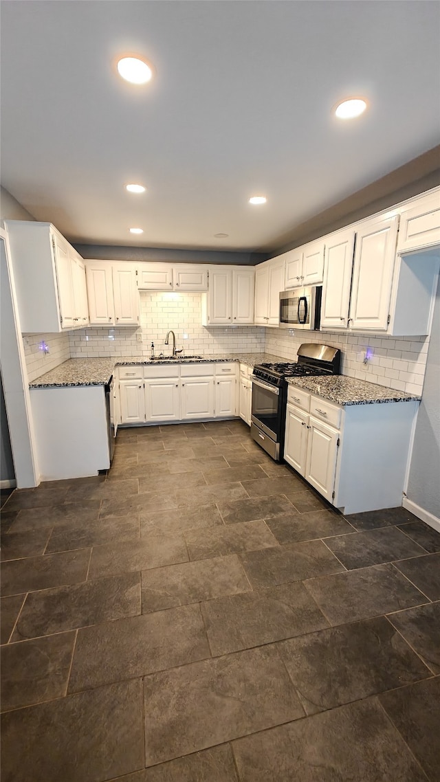 kitchen with white cabinets, backsplash, and stainless steel appliances