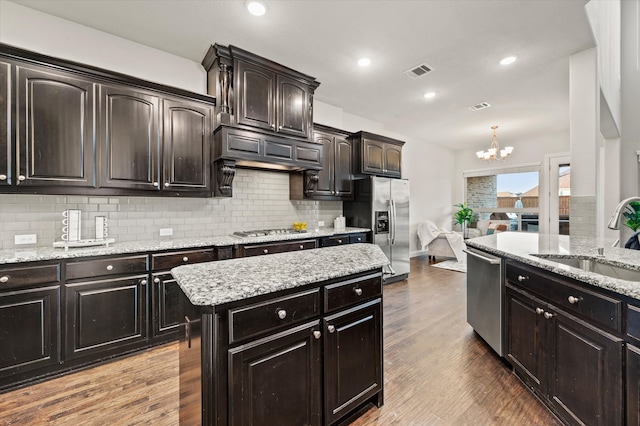 kitchen featuring sink, an inviting chandelier, light hardwood / wood-style flooring, decorative backsplash, and appliances with stainless steel finishes