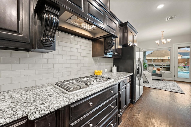 kitchen with decorative backsplash, appliances with stainless steel finishes, visible vents, dark wood-style floors, and an inviting chandelier
