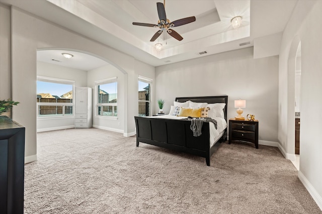 carpeted bedroom featuring ceiling fan and a tray ceiling