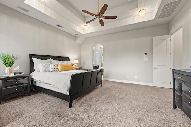 carpeted bedroom with a tray ceiling and ceiling fan