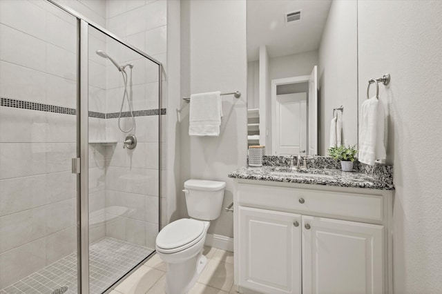 bathroom featuring tile patterned floors, toilet, vanity, visible vents, and a stall shower