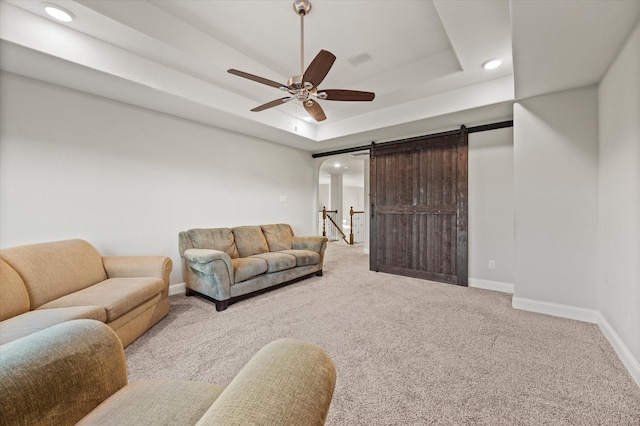 carpeted living room featuring a raised ceiling, a barn door, baseboards, recessed lighting, and a ceiling fan
