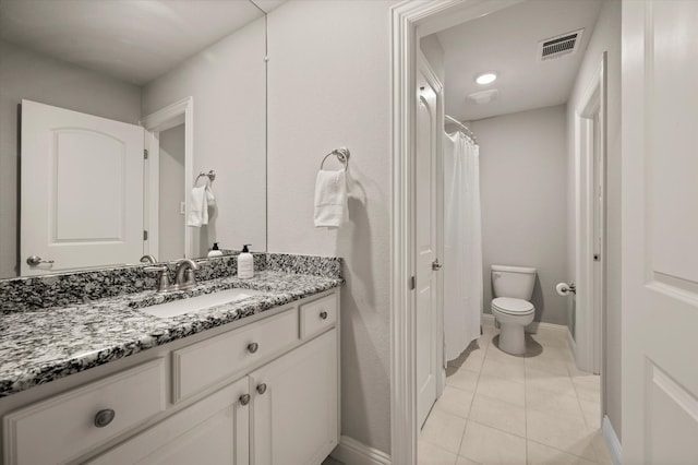 bathroom with toilet, vanity, and tile patterned floors