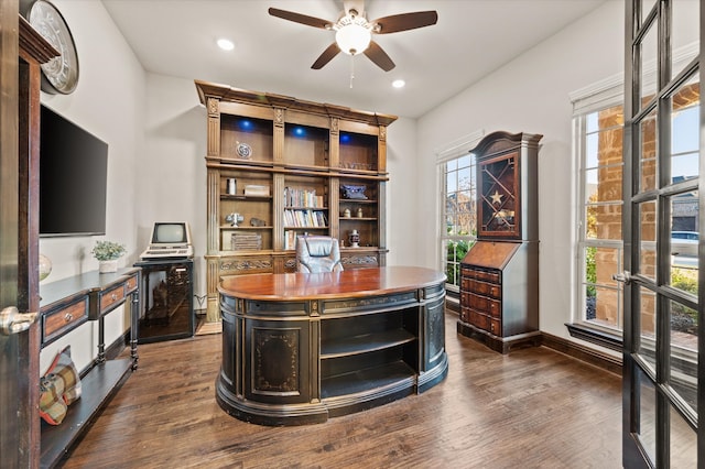 home office featuring plenty of natural light, ceiling fan, and dark wood-type flooring