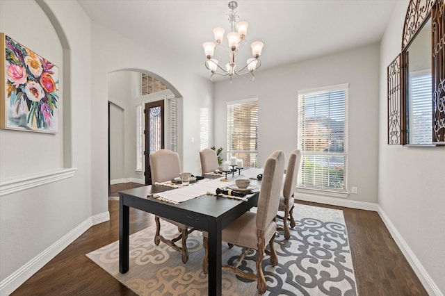 dining room with baseboards, arched walkways, an inviting chandelier, and wood finished floors
