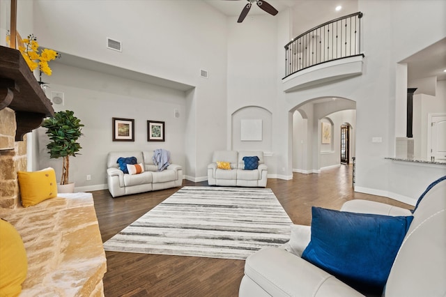 living room with a towering ceiling, dark hardwood / wood-style floors, and ceiling fan