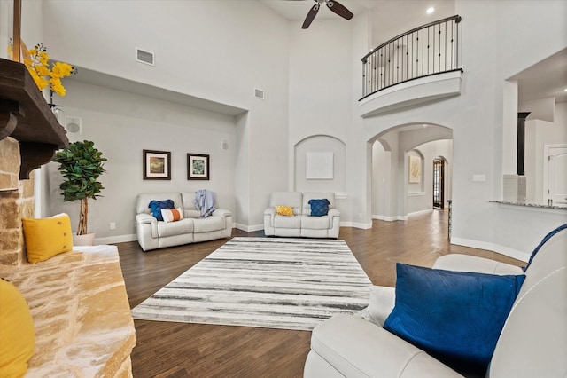 living area featuring a high ceiling, ceiling fan, visible vents, arched walkways, and wood finished floors