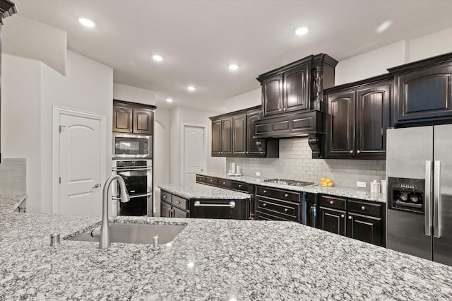kitchen with light stone countertops, recessed lighting, stainless steel appliances, backsplash, and a sink