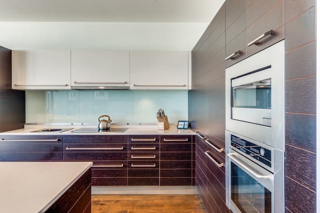 kitchen with stainless steel oven, ventilation hood, electric cooktop, hardwood / wood-style floors, and white cabinetry